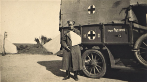 Офицер с рукой на перевязи у автомобиля Красного Креста. 1914-1916 гг.